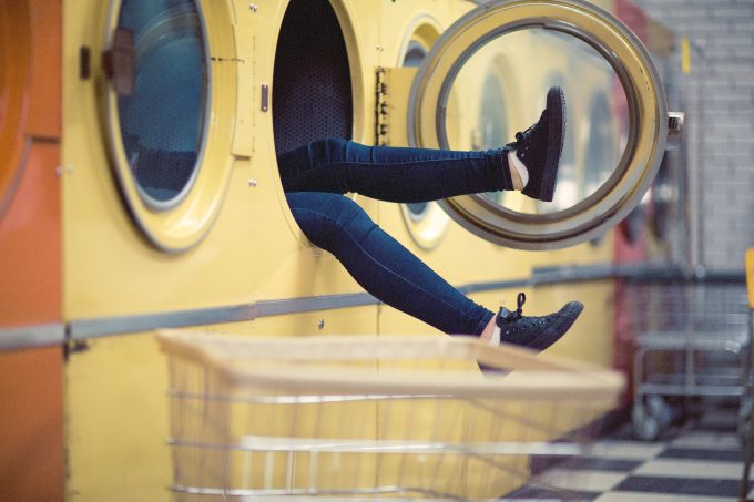 Eine Personsitzt in einer großen Waschmaschine, nur die Füße hängen raus